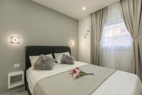 1 dormitorio con 1 cama con 2 almohadas y flores en Holiday apartments Stobrec en Split