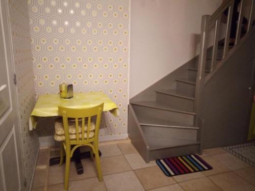 una mesa amarilla y sillas en una habitación con escaleras en Chez Sylvie et claude, en Milly-sur-Thérain
