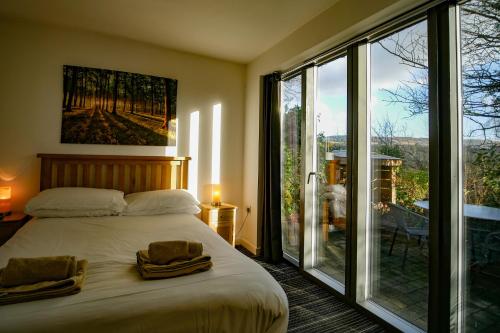 um quarto com uma cama e uma grande janela de vidro em Beili Glas Cottage em Pontardawe