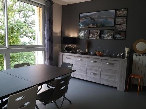 une cuisine avec une table et une grande fenêtre dans l'établissement Le Grand Val, à Lavastrie