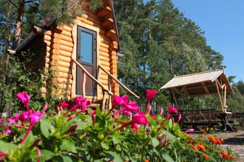 a log cabin with flowers in front of it at Pastoral wooden hauses in Velikiy Les