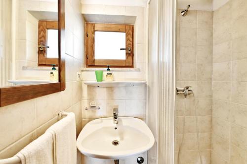 a white bathroom with a sink and a mirror at Adriatico Bungalow in Poreč