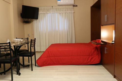 a bedroom with a red bed and a table with chairs at Esmeralda y Tucumán in Buenos Aires