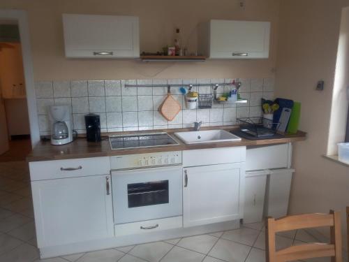 a kitchen with white cabinets and a sink at FeWo Gelnhausen in Gründau
