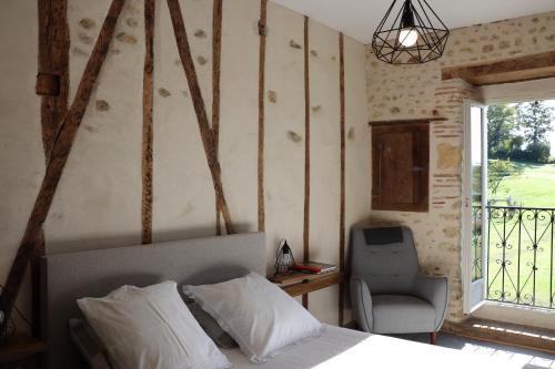 1 dormitorio con 1 cama, 1 silla y 1 ventana en Maison d'hôtes Marimpoey en Monein