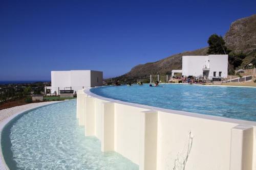 una piscina de agua con edificios en el fondo en Villa Laurum - Giardino degli allori - Castellammare del Golfo - Scopello, en Castellammare del Golfo