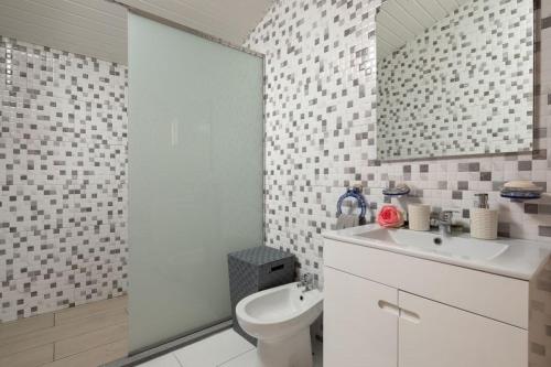 a bathroom with a toilet and a sink and a mirror at Casa Santana in Estreito da Calheta