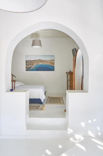a white room with a bed and an archway at 9 Muses Exclusive Apartments in Grikos