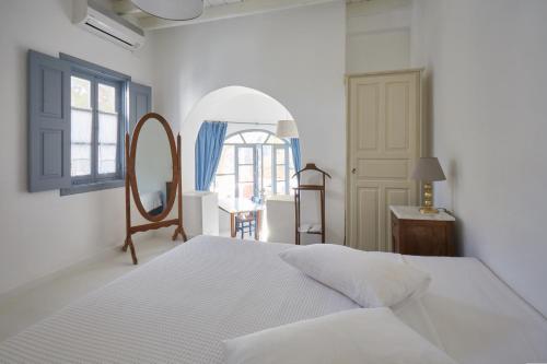 a white bedroom with a bed and a mirror at 9 Muses Exclusive Apartments in Grikos