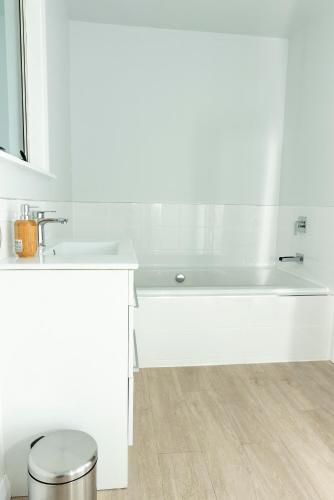 a white bathroom with a sink and a tub at The House at No 1 in Havelock North