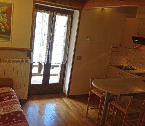 uma cozinha com uma mesa e uma porta com uma janela em Residence Casa dei Fiori em Alagna Valsesia