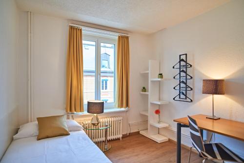 um quarto com uma secretária, uma cama, uma secretária e uma janela em Saint Georges Hotel em Zurique