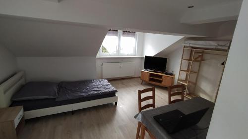 a small bedroom with a bed and a desk with a television at Wohnung Neunkirchen 3 in Neunkirchen am Brand