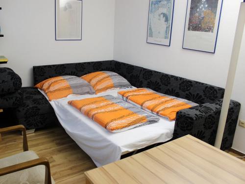 Una cama con almohadas de color naranja y gris. en Ferienwohnung Nimritz en Oppurg