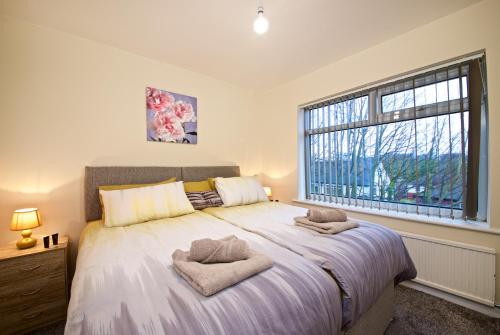 Beautiful Cozy Home With Free Parking في مانشستر: غرفة نوم بسرير كبير عليها منشفتين