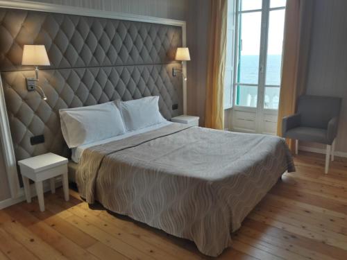 a bedroom with a large bed with a large headboard at Grand Hotel & des Anglais Spa in Sanremo