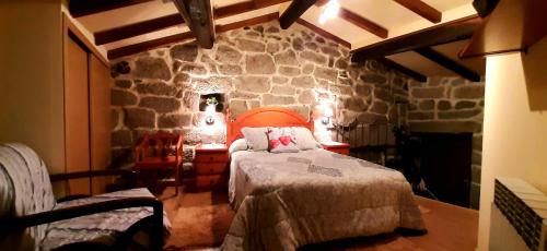 um quarto com uma cama e uma parede de pedra em Casa da Canella - En la Ribeira Sacra em Ourense