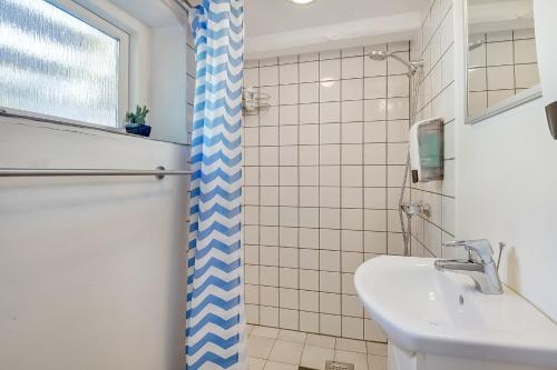 uma casa de banho com uma cortina de chuveiro azul e branco e um lavatório. em Sweethome Guesthouse em Esbjerg