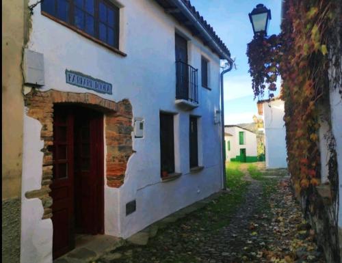 a white building with a red door on a street at Casa Farfarnicola in Aguafría