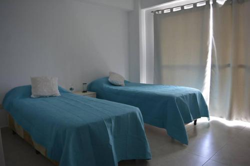 Cette chambre dispose de 2 lits avec des draps bleus et d'une fenêtre. dans l'établissement Salta Historica, à Salta