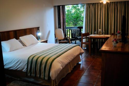 um quarto de hotel com uma cama, uma secretária e uma janela em Hotel Passarim em Capão Bonito