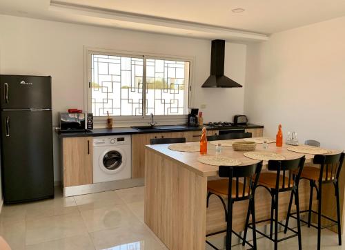 a kitchen with two tables and a refrigerator at Villa Lina Moderne toute équipée & Piscine in Midoun