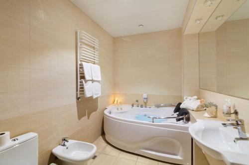 ein Badezimmer mit einer Badewanne, einem Waschbecken und einem WC in der Unterkunft Avalon Palace in Ternopil
