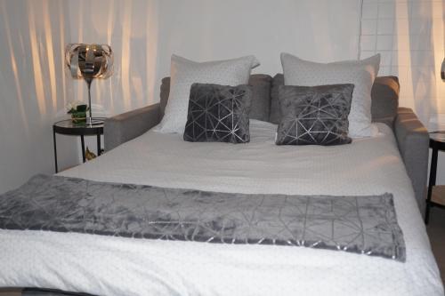 a bed with gray and white sheets and pillows at Appartement de standing in Berck-sur-Mer