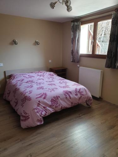 a bedroom with a pink bed and a window at RAND'UBAYE in Barcelonnette