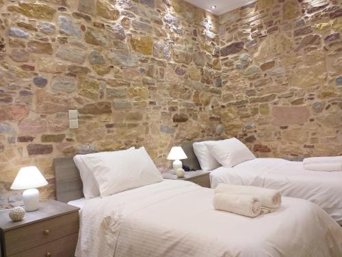 two beds in a room with a stone wall at CityZen Rooms Chios in Chios