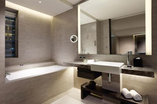 a bathroom with a sink, mirror, and bathtub at Humble House Taipei in Taipei