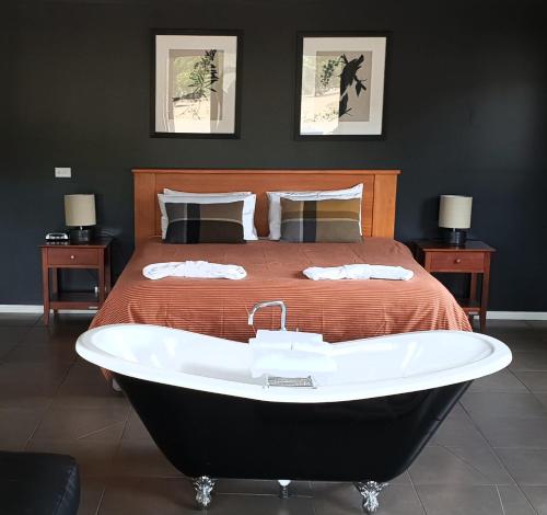 Blaze Rock Retreat في هولز غاب: غرفة نوم بسرير وحوض استحمام بجانب سرير
