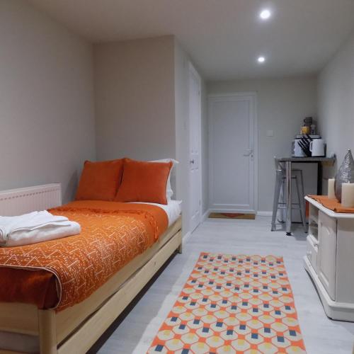 a bedroom with an orange bed and a rug at Lavender Oaks Studio in Worcester Park