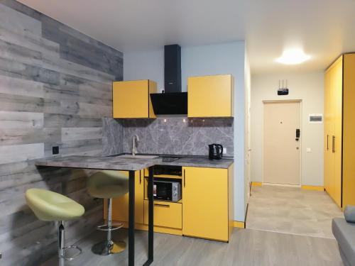 a kitchen with yellow cabinets and a counter with stools at Solo Apartment Kamenskaya in Kyiv
