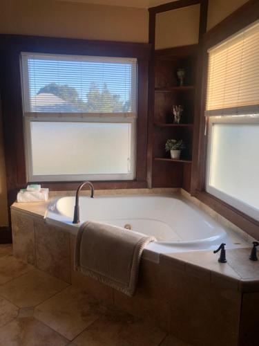 a large bath tub in a bathroom with two windows at Shorelight Inn in Benicia