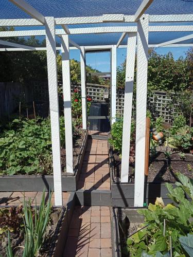 a garden with a white pergola in a garden at Moana View in Picton