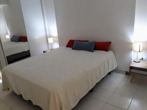 1 dormitorio con 1 cama blanca grande con almohadas rojas y azules en Cómodo y versátil en casco histórico en Salta