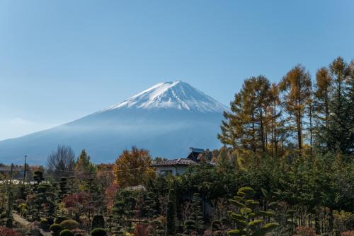 a mountain in the distance with a house in the foreground at Fujimien in Fujikawaguchiko