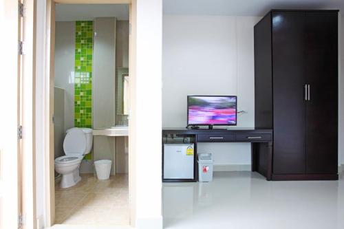 a bathroom with a toilet and a television on a desk at Garden Hill Hotel in Trang
