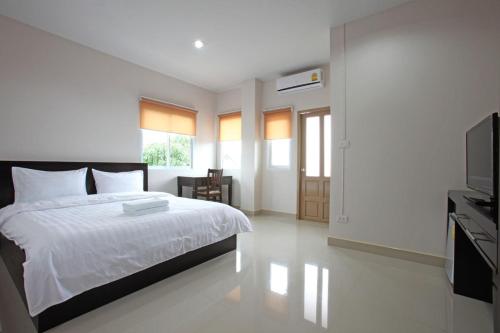 een slaapkamer met een wit bed en een televisie bij Garden Hill Hotel in Trang