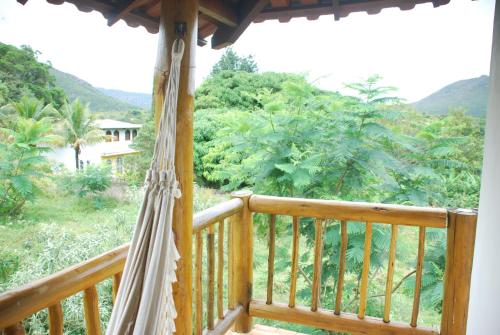 a porch with a hammock and a view of the forest at Casa do Capão in Vale do Capao