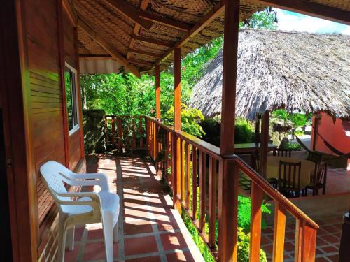 a porch of a house with two chairs and a thatch roof at Hostal Recuerdos del Tayrona in El Zaino