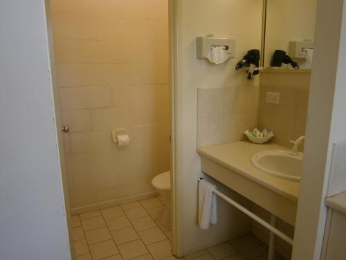 uma casa de banho com um lavatório, um WC e um espelho. em Kellys Motel Oakey em Oakey