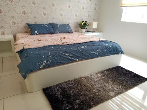 a bedroom with a bed with blue pillows and a rug at Permata Hanan Homestay Sungai Petani Kedah in Kampong Pinang