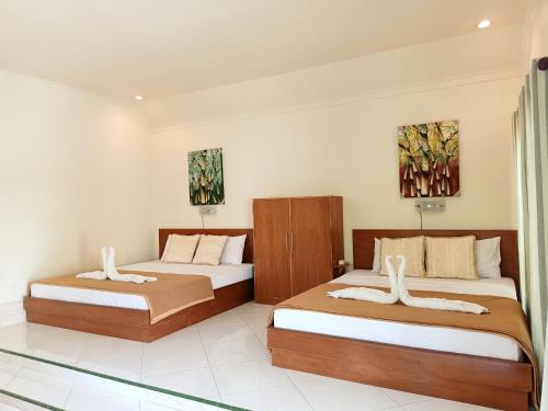 a bedroom with two beds and two paintings on the wall at Two Brothers Bungalows in Gili Meno