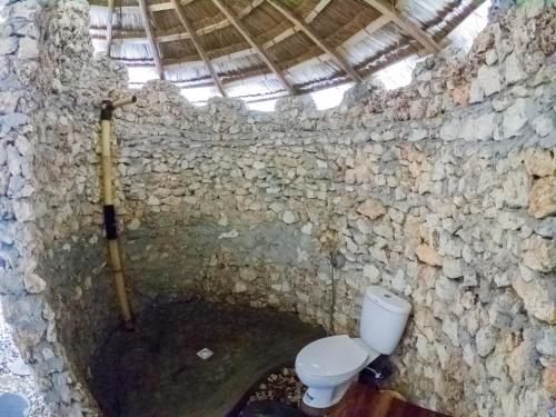 a stone bathroom with a toilet in a cave at Costa Beach Resort & Club in Waingapu