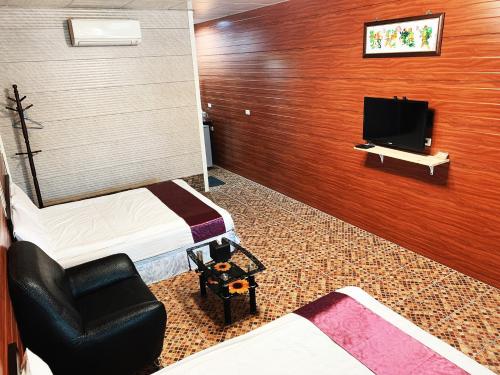 a room with two beds and a tv and a chair at Taroko Little Fish in Xincheng