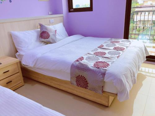 a bedroom with a large bed with purple walls at Yun Shan Shuei Country House in Fengping