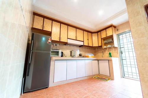 a kitchen with a stainless steel refrigerator and white cabinets at Star Light Homestay in Sitiawan