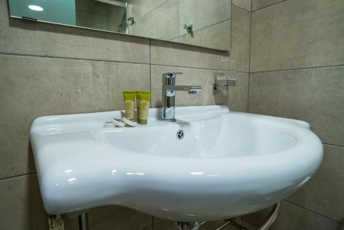 
a white sink sitting in a bathroom next to a mirror at Argo Hotel Piraeus in Piraeus
